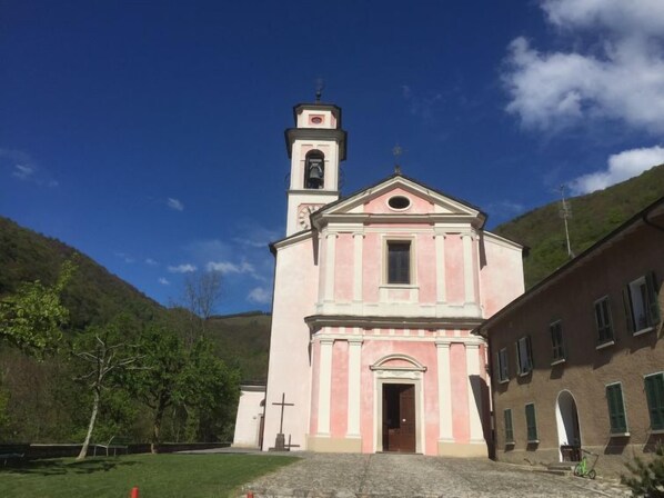 A church with a bell tower, a cross in front, and a stone pathway leading to the entrance.