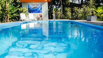 Una piscina al aire libre, sillones reclinables de piscina