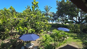 Un jardín con zona de estar, dos sombrillas y vistas a la playa.