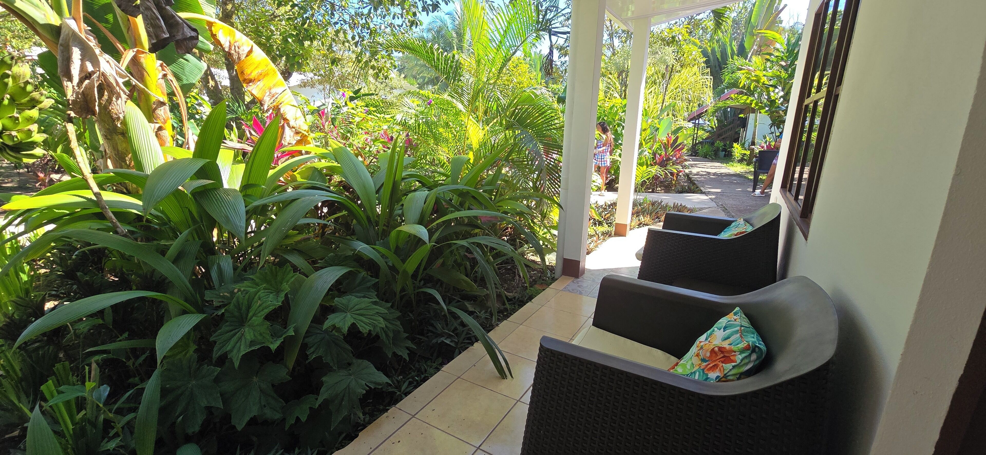 A covered outdoor seating area with a view of a lush garden.