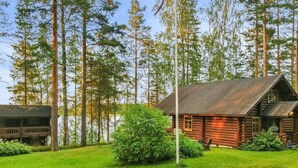 A rustic log cabin with a sloped roof, surrounded by a well-maintained lawn and tall trees. - Palkinniemi by Interhome (Punkaharju)