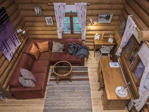 Ein gemütliches Blockhaus-Interieur mit einem Ecksofa, einem Esstisch und einem Korbwannenkorb.