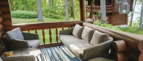 A wooden deck with a sofa, chairs, and a small table.