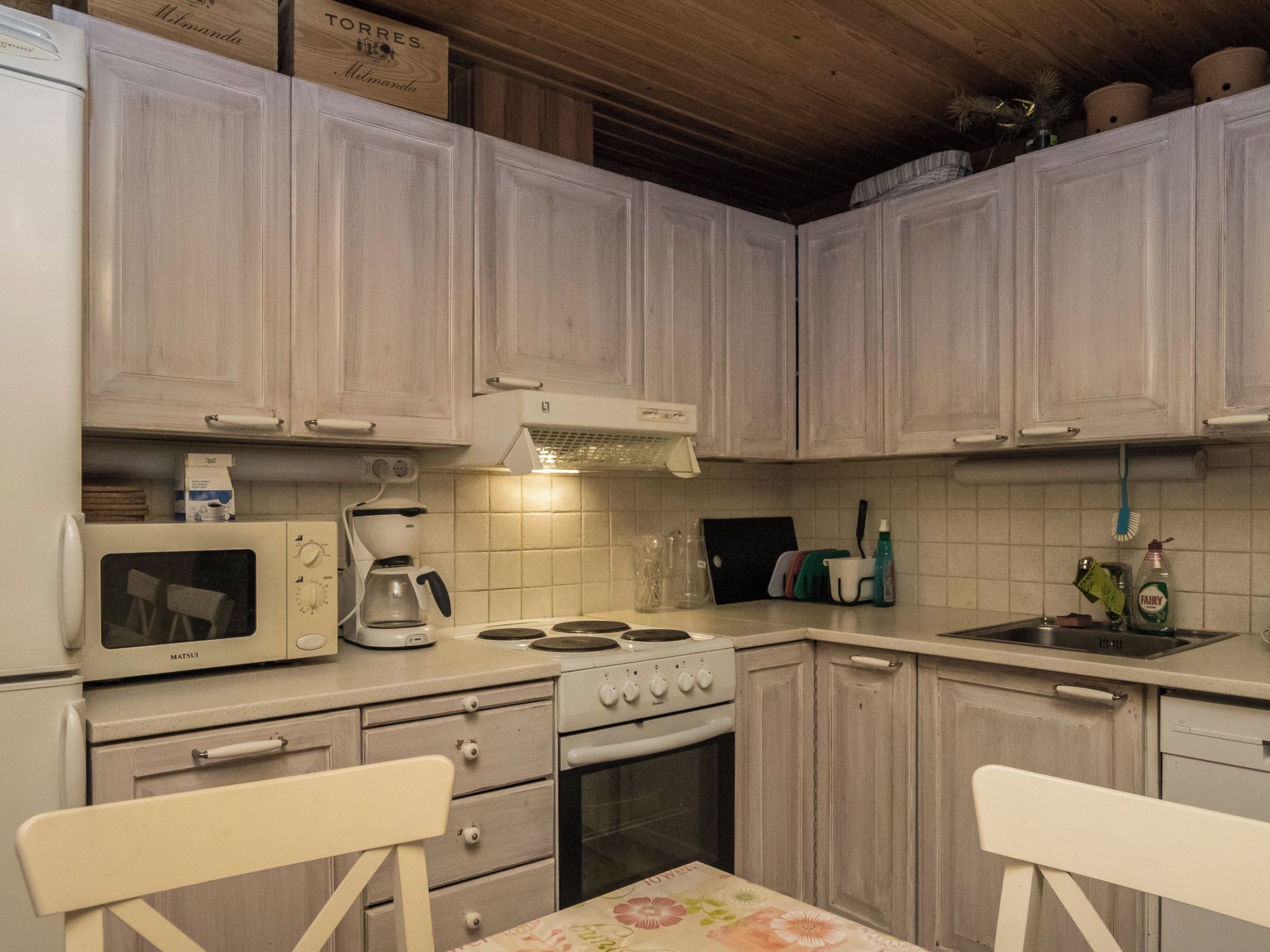 Una cocina con armarios blancos, estufa, microondas y cafetera.