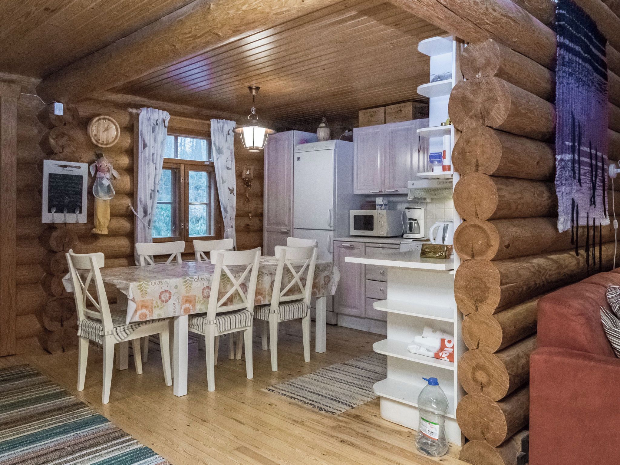 A cabin interior with a dining table, chairs, a refrigerator, a microwave, and a sink.