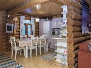 A cabin interior with a dining table, chairs, a refrigerator, a microwave, and a sink. - Palkinniemi by Interhome (Punkaharju)