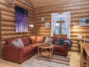 A log cabin interior with a red sofa, a small round table, and a window with curtains. - Palkinniemi by Interhome (Punkaharju)