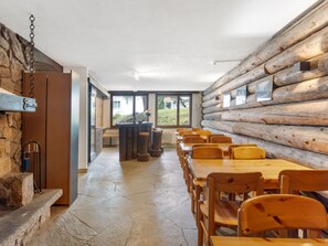 A dining area with wooden tables and chairs, stone flooring, and a log wall. - Parkareal Apt 404 by Interhome (Davos)