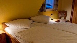A single bed with white bedding in a room with yellow walls and a sloped ceiling. - Am Nordkap by Interhome (Norddeich)