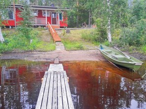 Puinen laituri johtaa talolle, jonka ulkoseinät ovat punaiset ja jossa on portaikko.