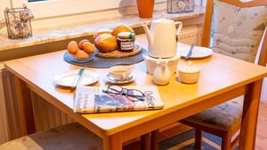 A wooden table with breakfast items, a newspaper, and a teapot.