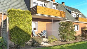 A two-story house with a sloped roof, a wooden balcony, and a garage.