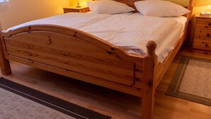 A wooden bed with a headboard, two bedside tables with lamps, and a rug on the floor.