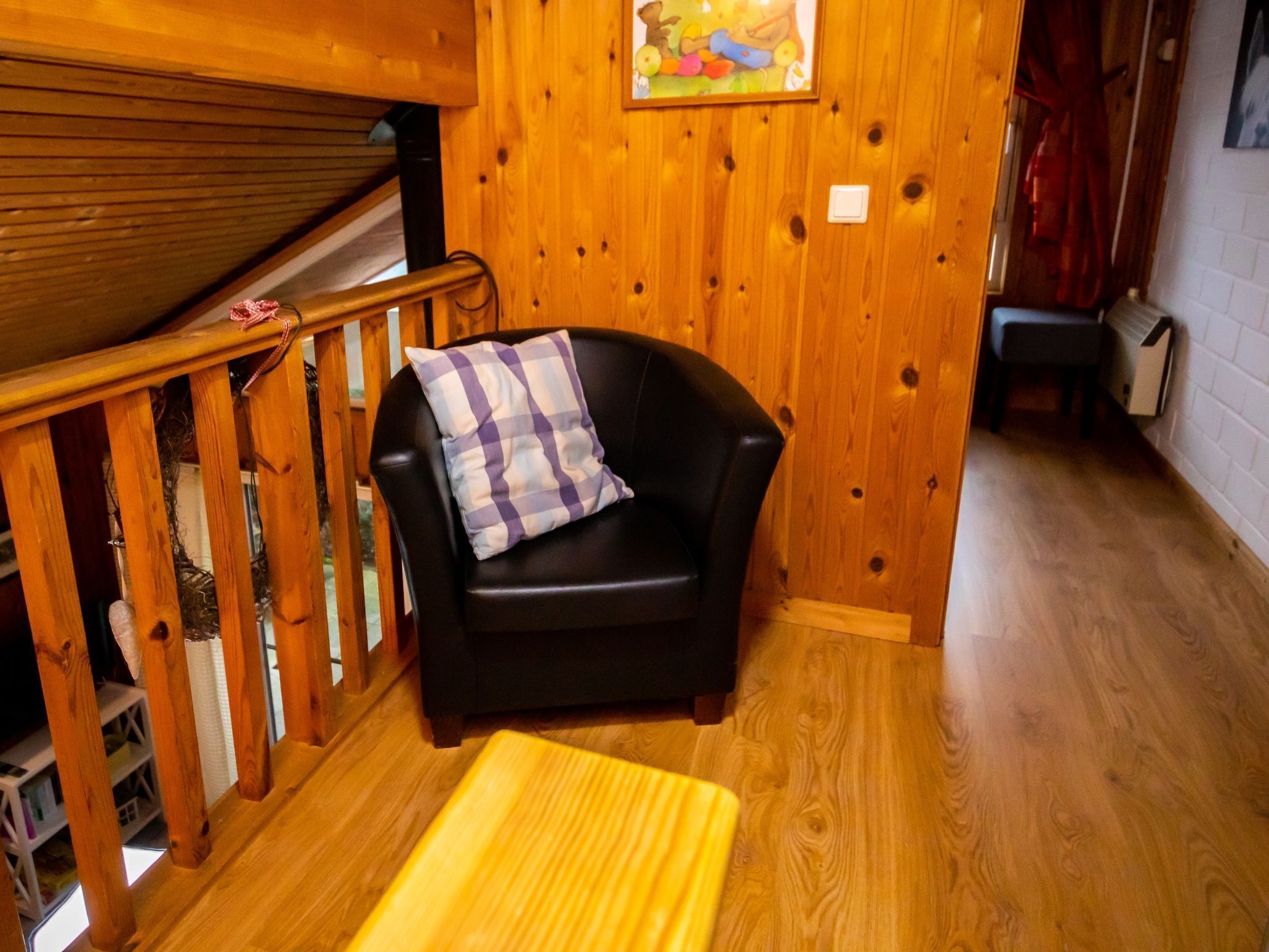Un interior de madera con una silla de cuero negro, un banco de madera y una escalera de madera.