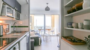 Moderni keittiö, jossa on sisäänrakennettu mikroaaltouuni, kahvinkeitin ja pesuallas. Keittiössä on myös ruokailutila, jossa on pöytä ja tuolit, sekä parveke, josta on näkymä.