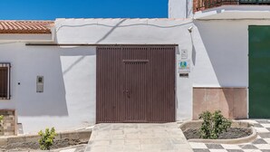 Un bâtiment avec une porte marron, un petit hall d’entrée et un trottoir à carreaux menant à l’entrée.