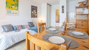 A cozy room with a bed, a dining table set for two, and a small side table with a lamp. - Le Capitole by Interhome (Fréjus)