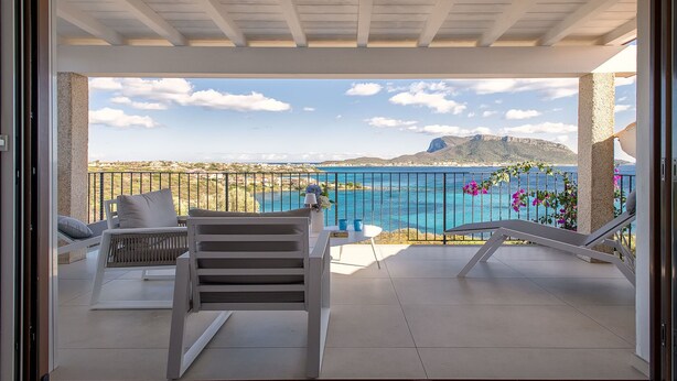 Ein Balkon mit Blick auf das Meer und eine gebirgige Landschaft.