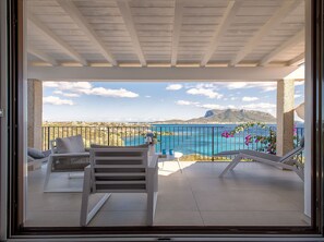 En balkon med udsigt over havet og et bjerglandskab.