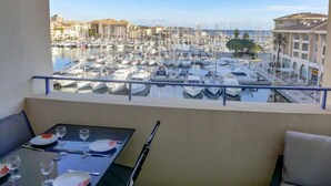 Un balcon avec une table dressée pour le dîner, donnant sur une marina où sont amarrés de nombreux bateaux.
