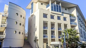 Un immeuble à plusieurs étages doté de balcons, d’un restaurant et d’une enseigne indiquant la présence d’un restaurant et d’une pizzeria.