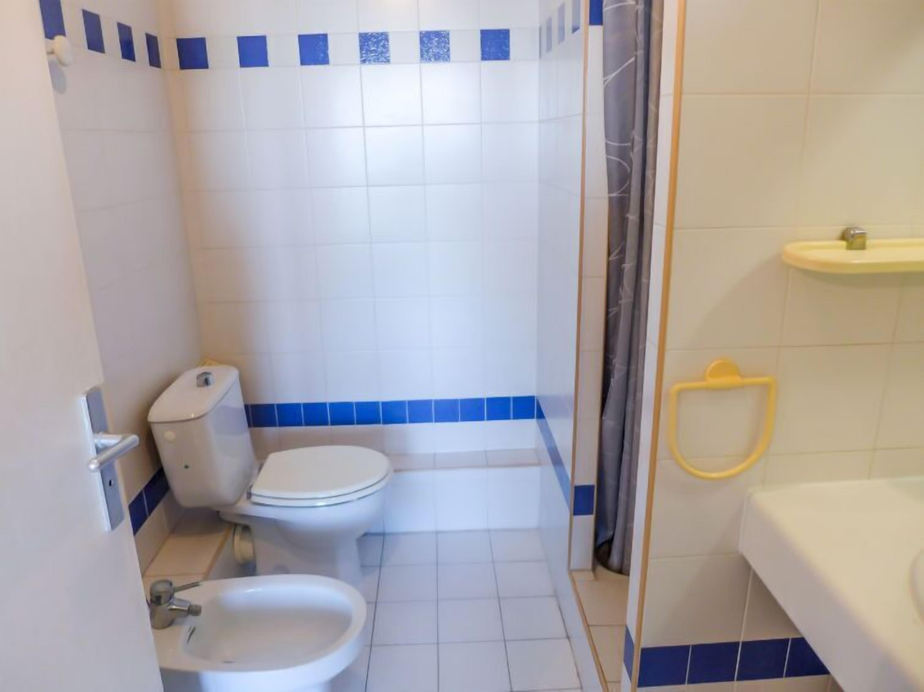 A small bathroom with a toilet, bidet, and sink.
