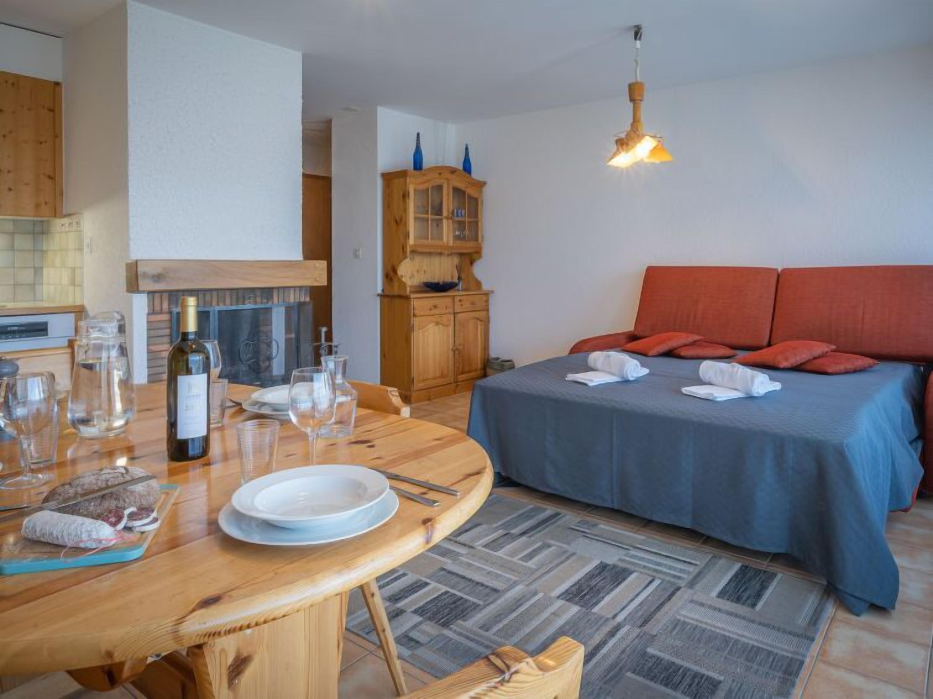 Une pièce confortable avec un lit, une table à manger avec des assiettes et des verres, un buffet en bois et un luminaire suspendu.