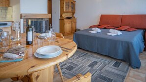 Una habitación acogedora con cama, una mesa de comedor con platos y vasos, un armario de madera y una lámpara colgante.
