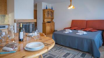 Une pièce confortable avec un lit, une table à manger avec des assiettes et des verres, un buffet en bois et un luminaire suspendu.