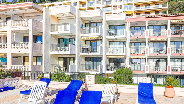 Un hôtel à plusieurs étages doté de balcons, d’un espace extérieur aménagé pour s’asseoir et d’une piscine.
