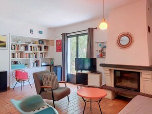 Ein Wohnzimmer mit Kamin, Fernseher, Bücherregal und Essbereich.