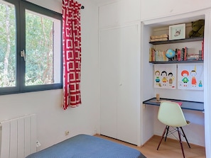 Une pièce avec une fenêtre, un radiateur, un bureau avec une chaise et une bibliothèque remplie de livres et comportant un globe terrestre.