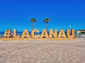 Ein hölzernes Schild mit der Aufschrift „#LACANAU“ und „JAMAIS COMME AILLEURS“ vor blauem Himmel.