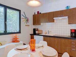Une cuisine moderne avec des meubles en bois, un lave-vaisselle et un coin repas aménagé pour quatre personnes.