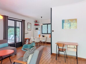 A modern living room with a sofa, chairs, a dining area, and a desk.