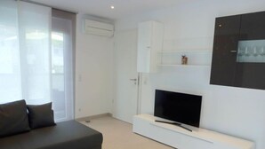 A modern living room with a sectional sofa, a flat-screen TV on a white entertainment unit, and a glass cabinet above the TV. - Apartment Brake by Interhome (Offenburg)
