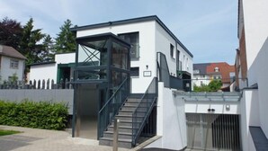 A modern two-story building with a glass elevator, a staircase, and a gated entrance. - Apartment Brake by Interhome (Offenburg)