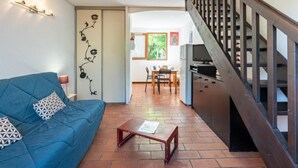 Un salon avec un canapé bleu, une table basse en bois et un escalier doté d’une rampe en bois.