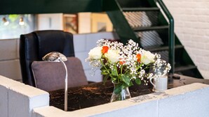 A reception area with a black leather sofa, a small table with a vase of flowers, and a staircase in the background. - Holly Lodge Coach House by Interhome (London West)