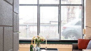 A living room with a glass coffee table, a vase with flowers, and a bottle of champagne. - Holly Lodge Coach House by Interhome (London West)