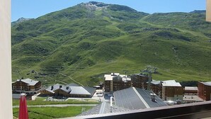 Vista de la montaña con un pueblo abajo, que incluye edificios y un telesilla.