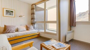 Una habitación acogedora con una cama, una mesita y un ventanal con cortinas.