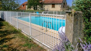 A swimming pool with a white fence, surrounded by grass and lavender plants. - La Grange by Interhome (Gramat)