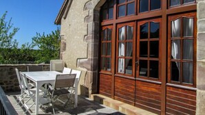An outdoor patio with a stone table and chairs, a wooden door with glass panels, and a stone wall. - La Grange by Interhome (Gramat)
