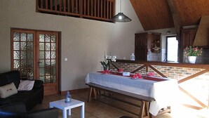 A spacious living area with a high ceiling, a dining table set for a meal, a sofa, and a small table with a lantern. - La Grange by Interhome (Gramat)
