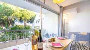 A dining table set with wine bottles, glasses, and plates, overlooking a balcony with greenery. - Le Grand Pavois by Interhome (Port Camargue)