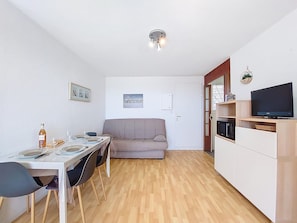 A compact living space with a dining area, a sofa, a TV, and a kitchenette.