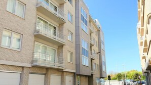 Un immeuble résidentiel à plusieurs étages, doté de balcons, de grandes fenêtres et de portes de garage.