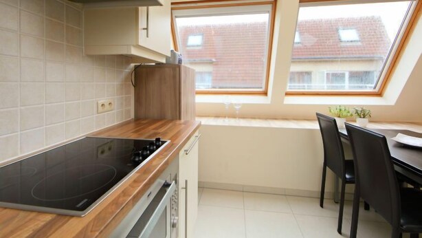 Une cuisine moderne dotée d’un plan de travail en bois, d’un four encastré et d’un coin repas avec une table et des chaises.