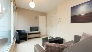 Un salon moderne avec un canapé, une table basse, un téléviseur posé sur un meuble en bois et un tableau accroché au mur.